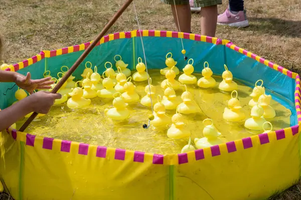 stock image A vibrant duck fishing game enthralls children at a summer festival, blending fun and simple competition