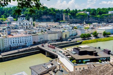 Salzburg, Salzburg - Avusturya - 06-18-2021: Güneşli bir gökyüzü altında köprüleri ve barok mimarisi olan Salzburg 'un tarihi merkezi, Salzach nehri manzarası