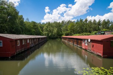 Wusterhausen, Brandenburg - Almanya - 06-28-2022: Teknelerin depolandığı ve hafta sonunuzu ve tatillerinizi geçirebileceğiniz yeşil bir su kütlesi üzerinde üst üste iki sıra tekne hangarı.