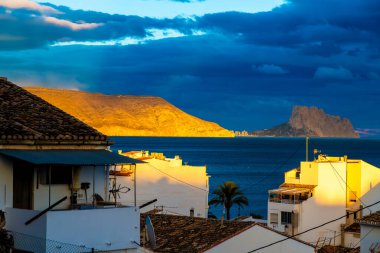 Altea, Alicante - İspanya - 01-05-2024: Akşam ışığı Altea 'nın beyaz binalarının arkasındaki dağı yıkıyor