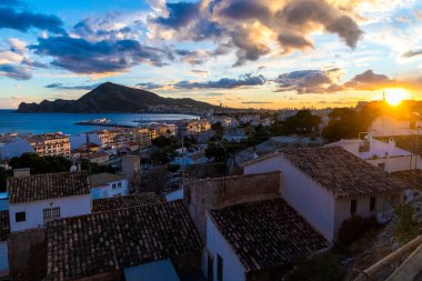 Altea, Alicante - İspanya - 01-05-2024: Gün batımı Altea 'nın ufuk çizgisini deniz kenarında bir dağ zeminine doğru aydınlatıyor