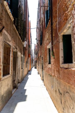 Venedik, Veneto - İtalya - 06-09-2021: Venedik 'te kırsal duvarları ve kapalı panjurları olan güneşli dar bir sokak
