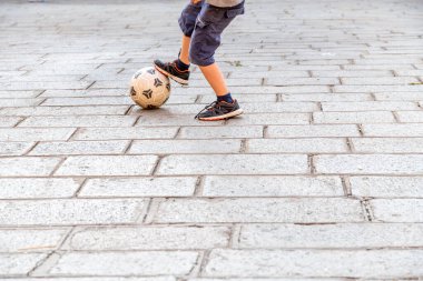 Venedik, Veneto - İtalya - 06-09-2021: Bir çocuğun kaldırımda top sürerken kaldırım taşı üzerinde futbol topuna yakın çekim yapması