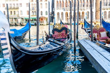 Venice, Veneto - Italy - 06-10-2021: Elegant gondolas moored by a wooden pier against a backdrop of Venice's grand buildings clipart
