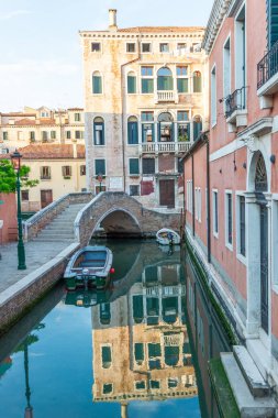 Venedik, Veneto - İtalya - 06-10-2021: Venedik 'teki sakin kanal süslü binaları yansıtıyor ve alacakaranlıkta kemerli bir köprü