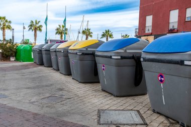 Puerto de Mazarron, Murcia - İspanya - 01-18-2024: İspanyol gezinti güvertesinde atık ayıklamak için çok renkli geri dönüşüm kutuları sıralanması