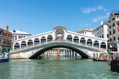 Venedik, Veneto - İtalya - 06-10-2021: İkonik Rialto Köprüsü Venices Büyük Kanalı üzerinde açık mavi bir gökyüzüne doğru ilerliyor