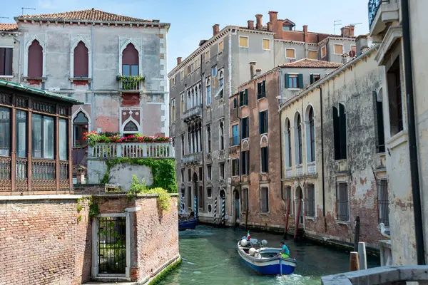 Venedik, Veneto - İtalya - 06-09-2021: Tekne, tarihi Venedik mimarisi ile çevrili sessiz bir kanalda nazikçe geziniyor