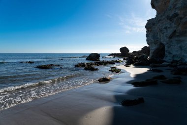 Cabo de Gata, Almeria - İspanya - 01-23-2024: Kayalık oluşumlar ve Cabo de Gata 'da hafif dalgalarla kaplı deniz manzarası, güneş ışığıyla yıkandı