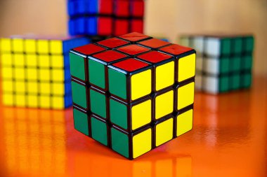 Canlı turuncu bir masada canlı renkler sergilenen üç Rubik küpü.