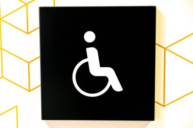 Bautzen, Saxony - Germany - 04-10-2021: Black and white sign with universal accessibility symbol set against a patterned background clipart
