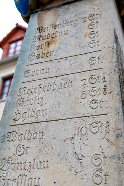 Loebau, Saxony - Germany - 04-17-2021: A close-up of a well preserved, yet historic milestone in Lbau showing distances to cities, with weathered inscriptions, some of them missing