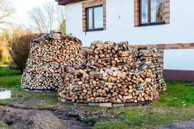 Brieselang, Brandenburg - Almanya - 03-11-2021: Beyaz bir evin önünde tuğla aksanlı ve kullanılmayı bekleyen iki büyük odun yığını