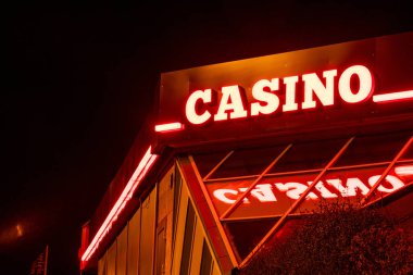 Bautzen, Saksonya - Almanya - 04-10-2021: Canlı kırmızı neon CASINO işareti geceyi aydınlatıyor, bina yapısını yansıtıyor