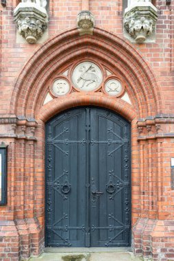Loebau, Saksonya - Almanya - 04-17-2021: Nikolaikirche 'nin süslü kapılı mimari ayrıntıları, her iki tarafında da Loebau' da sembollerle çevrili, bayrak tutan bir koyunun oyması