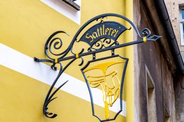 Loebau, Saksonya - Almanya - 04-17-2021: Artisan parlak sarı bir duvara monte edilmiş altın bir amblem ile demir kalkan yaptı