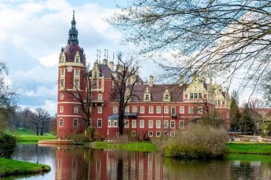 Bad Muskau, Saksonya - Almanya - 04-18-2021: Muskau Parkı 'nda yuva yapmış Iconic Schloss Muskau, yemyeşil bir göletin ortasında duruyor