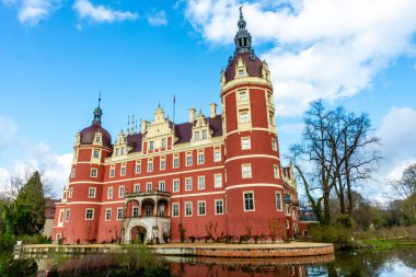 Bad Muskau, Saksonya - Almanya - 04-18-2021: Muskau Parkı 'nda yuva yapmış Iconic Schloss Muskau, yemyeşil bir göletin ortasında duruyor