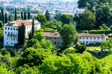 Vicenza, Venetien - İtalya - 06-12-2021: Canlı yeşillikler arasında yer alan tarihi beyaz binalar Vicenza, İtalya ve huzurlu manzarasını gözden kaçırıyor