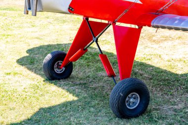 Caorle, Venetien - Italy - 06-14-2021: Vintage red biplane on a lush Italian meadow, showcasing front wheels and wings clipart