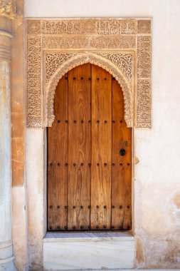 Granada, Granada - İspanya - 01-30-2024: Alhambra 'da süslü oyulmuş bir kemer içinde tarihi ahşap bir kapı.