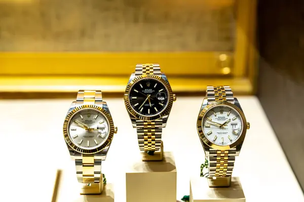 Vicenza, Venetien - İtalya - 06-12-2021: Zarafet ve lüksü sembolize eden altın bir zemin üzerinde sunulan üç adet özel Rolex kol saati