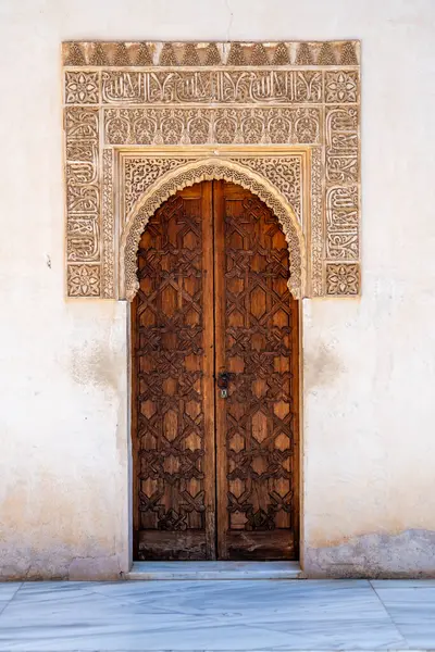 Granada, Granada - İspanya - 01-30-2024: Alhambra 'da süslü oyulmuş bir kemer içinde tarihi ahşap bir kapı.