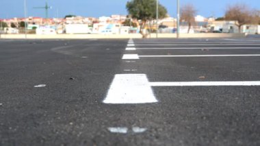 Park yerleri için yeni asfalt işaretleri. Arka planda bir şehir ve mavi gökyüzü olan bir otoparkta beyaz boya..