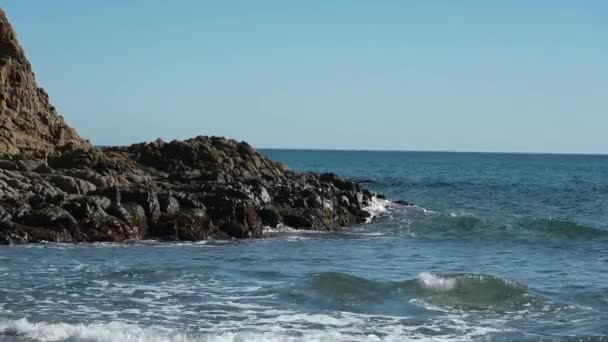 一幅幅海浪的景象 白沫罩着岩石破浪而出 然后在蓝天和阳光下向着海滩飞去 — 图库视频影像