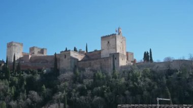 Alhambra 'yı Granada, İspanya' nın dışından, sağdan sola, parlak mavi bir gökyüzünün altından süpür. Ön planda, eski moda bir anten görülebilir.