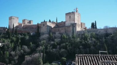 Alhambra 'yı Granada, İspanya' nın dışından, sağdan sola, parlak mavi bir gökyüzünün altından süpür. Ön planda, eski moda bir anten görülebilir.