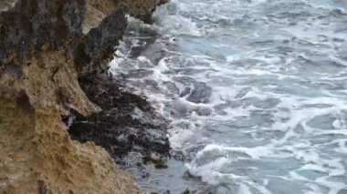 Akdeniz 'in dalgalarının koptuğu, suyu döndürdüğü ve kayaların üzerinden aktığı kayalık bir sahil şeridi. Bu süreçte su köpürüyor..
