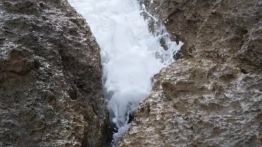 Ortasında küçük bir kaya yarığı olan bir kaya yarığı, deniz suyunun sürekli dalgalarla yıkandığı, köpüklü bir su yüzeyinde yol açtığı yer..