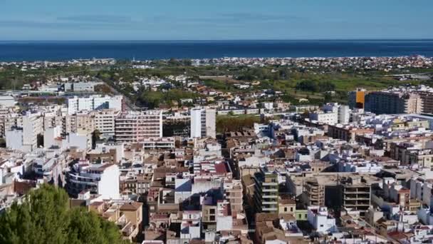 全景扫荡了西班牙的奥里瓦镇 背景是大海 前景是树木和灌木丛 在市中心 可以看到许多多层的房子 — 图库视频影像