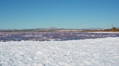 Tuzlu su birikintisini tuzlu su üretimi için süpür. Önde gelen kırmızı, tuzlu ve mineral zengini su için. Sert rüzgarlar altında, kalın bir köpük tabakasını kıyıya yıka. Kırmızı su yüzeyinde dalgalar