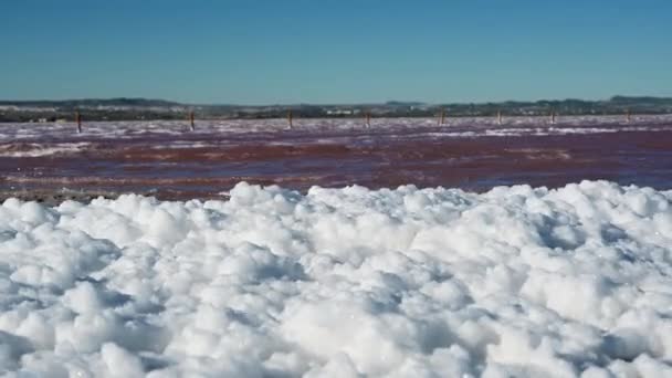 咸水泻湖咸水泻湖一种咸水泻湖 用于产盐 带有红色 咸水和矿物质丰富的水 在强风中冲刷着厚厚的一层泡沫冲到岸上红水表面的波浪 — 图库视频影像