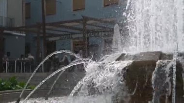 Denia, Alicante - İspanya 11-04-2023: Kaynayan suyun içinden parlayan ve bir kafe veya restoranın önünde bir sürü su akışı olan daha büyük bir çeşme