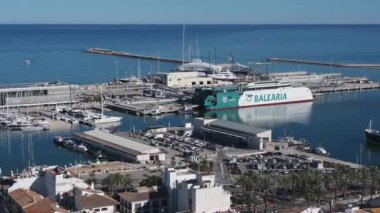 Denia, Alicante - İspanya 11-04-2023: Denia limanının çok sayıda limanı, liman binaları, depoları, özel yatları, motorbotları ve mavi gökyüzü ve güneş ışığının altında büyük bir yatı olan manzarası