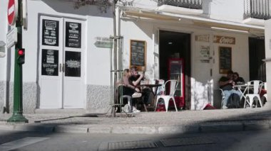 Granada, Granada - İspanya 02-03-2024: Garsonların servis yaptığı ve gençlerin vakit geçirdiği kaldırımda masaları olan pitoresk bir sokak kafesinde soldan sağa yavaş tava