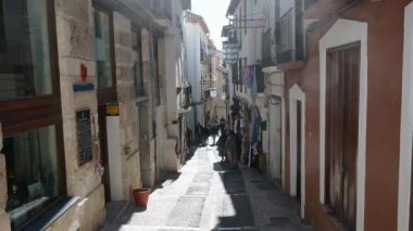 Granada, Granada - İspanya 02-03-2024: Granada 'da güneşten sırılsıklam olmuş dar bir sokağa bakın. Yoldan geçenlerin çoğu yokuş aşağı gidiyor. Işığın ve gölgenin etkileşimi özellikle güzeldir.