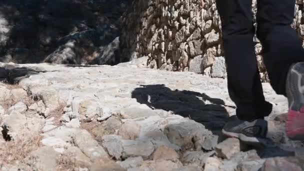 西班牙阿利坎特 德纳亚 一个人沿着一条大致铺成的历史性道路沿着历史城墙走上坡时的两条腿和脚 太阳在照耀着 — 图库视频影像