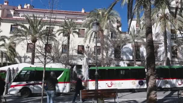 格拉纳达 格拉纳达 西班牙格拉纳达 格拉纳达的一个广场 一辆装有火车拖车的公共汽车载着游客绕城一周 广场上有许多行人和棕榈树 — 图库视频影像