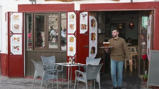 グラナダ グラナダ スペイン02 2024 ウェイターは 椅子付きの空のテーブルに立っているドリンクのトレイを持つレストランから出てきます 写真付きのメニューが外に表示されます — ストック動画