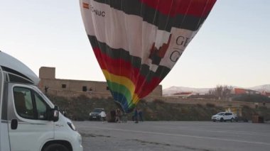 Guadix, Granada - İspanya 01-25-2024: Sıcak hava ile doldurulduktan sonra büyük, renkli bir sıcak hava balonu görkemli bir şekilde havaya yükselir