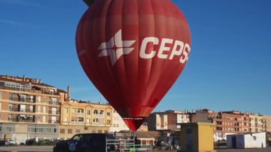 Guadix, Granada - İspanya 01-25-2024: Bir şehir manzarasının ön planında şişirilmiş bir sıcak hava balonu havaya yükseliyor