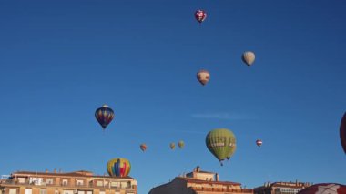 Guadix, Granada - İspanya 01-25-2024: Birçok sıcak hava balonu aynı anda mavi, bulutsuz gökyüzüne yükseliyor, sabah güneşi altında yüzerek.