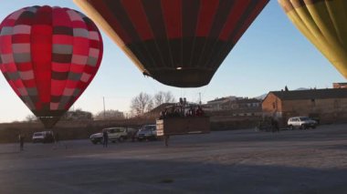 Guadix, Granada - İspanya 01-25-2024: Bir sıcak hava balonunun yükselişi çok büyük bir yolcu gondolu ile sabah ışığı altında. Arka planda araçlar görünür..