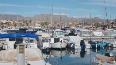 Mazarron, Murcia - İspanya 03-26-2024: Çok sayıda yelkenli ve motorlu tekne ile Puerto de Mazarron marinasının üzerinde bir tepsi. Arka planda, dağlar parlak mavi bir gökyüzünün altında yükselir..