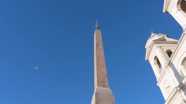 Roma, Latium - İtalya 11-22-2022: Sallustiano Obelisk 'ten Roma' daki Trinit dei Monti 'ye kadar Pan, aşağıdan parlak mavi gökyüzüne doğru çekildi. Dikili taşın ve kilisenin üst kısımları odak noktasında..