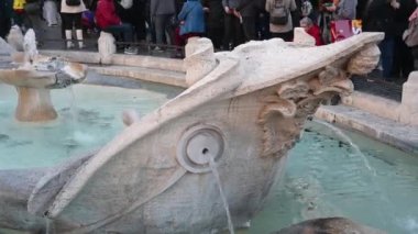 Roma, Latium - İtalya 11-22-2022: Fontana della Barcaccia, fıskiyelerden gelen temiz su kabarcıklarıyla, pek çok sanatsal ayrıntıya sahip taştan yapıldı. Arka planda turistler.